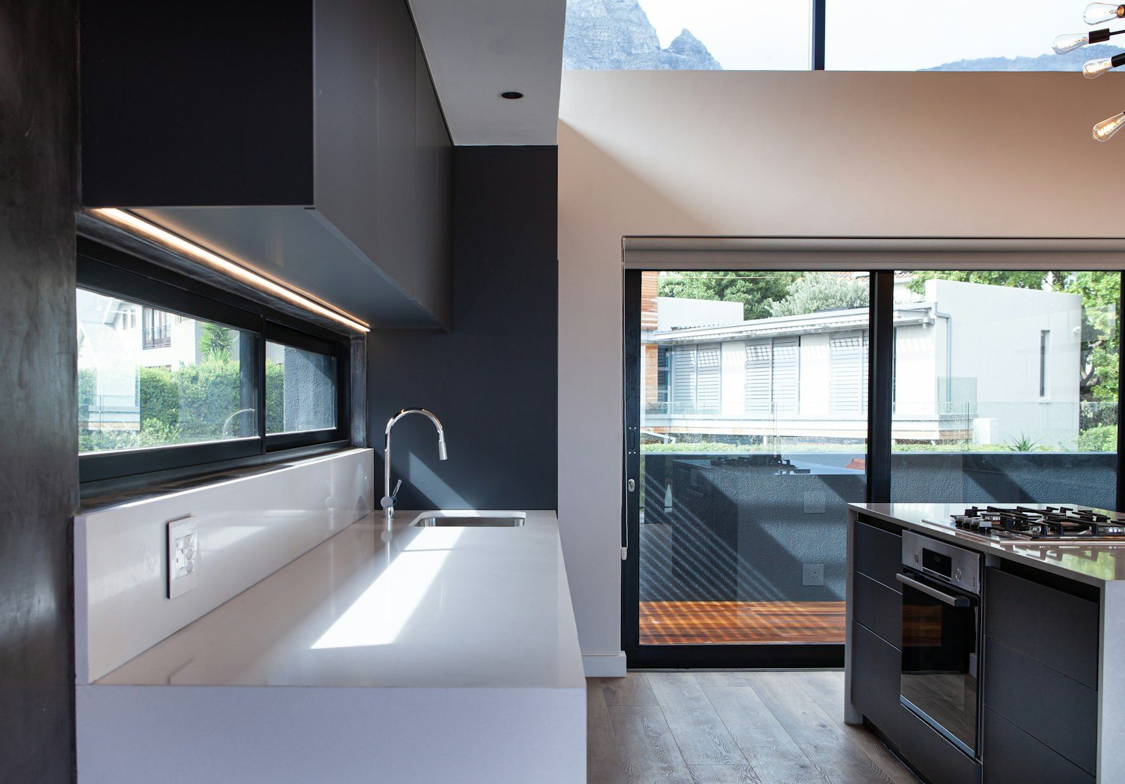 Puerta corredera acristalada de marco oscuro junto a una cocina