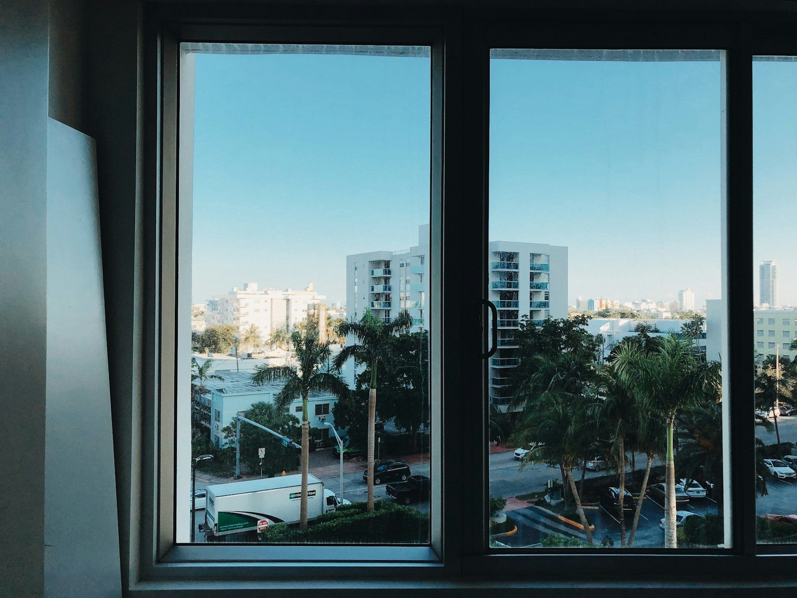 Ventana de dos hojas con marco oscuro y vistas urbanas como referencia para carpintería aluminio